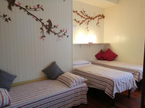 3 camas en una habitación con paredes blancas y almohadas rojas en B&B A Casa Dei Nonni, en Capua