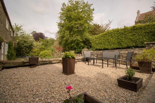 a patio with chairs and potted plants in a yard at Jasmine Cottage Lastingham North Yorkshire in Pickering
