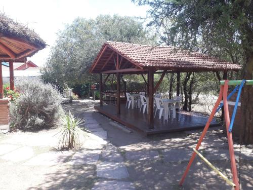 a wooden gazebo with white tables and chairs at Complejo Sagrado Corazón in Merlo