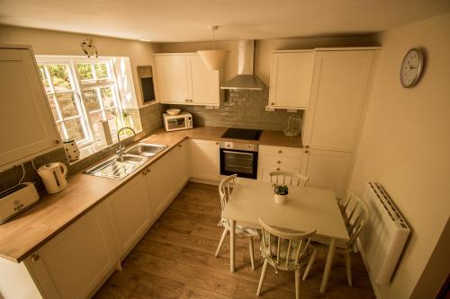 een keuken met een wastafel en een tafel met stoelen bij Jasmine Cottage Lastingham North Yorkshire in Pickering