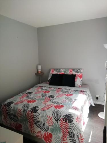 a bedroom with a bed with a floral bedspread at T2 chaleureux sur talence in Talence