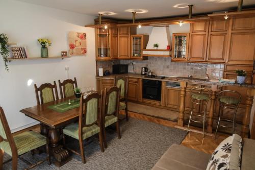 a kitchen with wooden cabinets and a table and chairs at Apartman Kaya in Đakovo