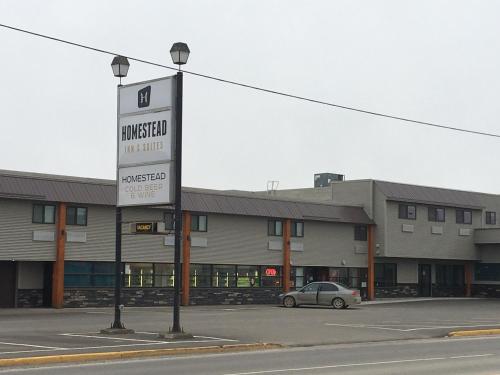 a car parked in a parking lot in front of a building at Homestead Inn & Suites in Vanderhoof