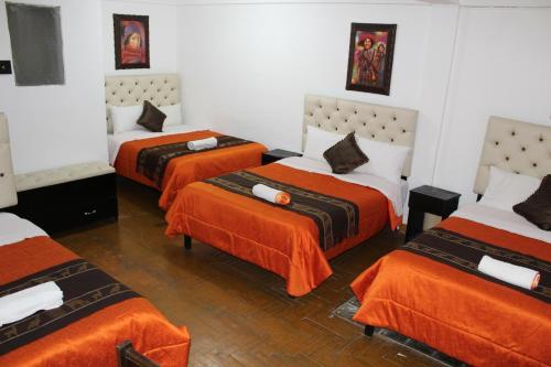 3 camas en una habitación con sábanas naranjas en Imperial Golden House Inn en Cusco
