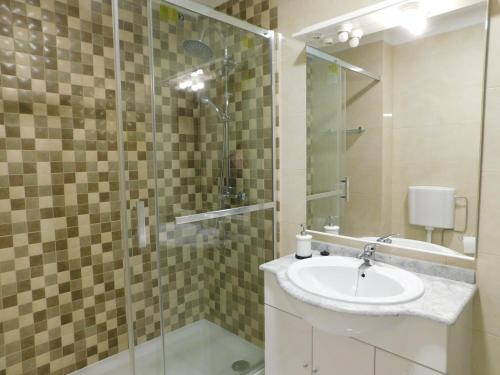 une salle de bain avec un lavabo et une douche en verre dans l'établissement Estrela Mar Marina Villa, à Quarteira