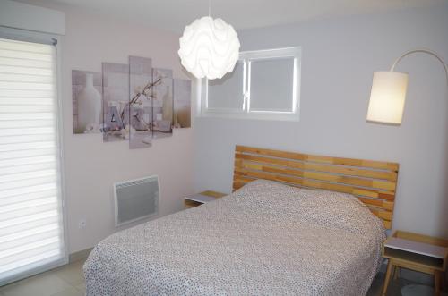 1 dormitorio con cama y lámpara de araña en Gîte lumineux avec terrasse, jardin et parking, en Lédenon