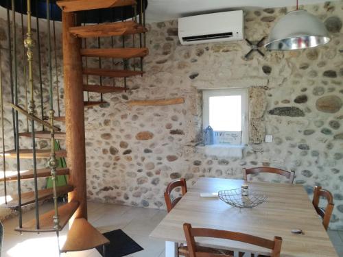 a dining room with a wooden table and a spiral staircase at La Chabottine Vercors in Saint-Just-de-Claix
