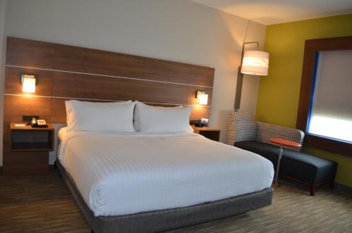 a hotel room with a large bed and a chair at Holiday Inn Express & Suites - Charlotte NE - University Area by IHG in Charlotte