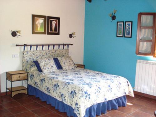 a bedroom with a bed with a blue wall at Apartamentos Rurales El Molín de Panizal in San Cosme