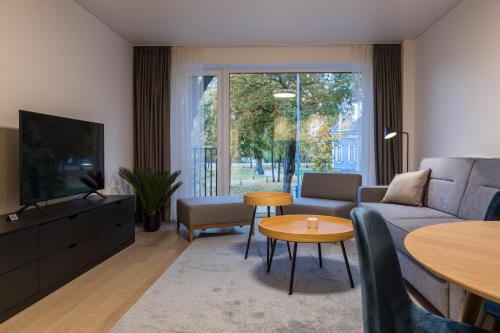 een woonkamer met een bank, een tv en een tafel bij Apartment Hotel Laisve in Druskininkai