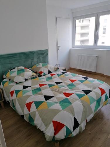 - une chambre avec un grand lit et une couette colorée dans l'établissement T3 Nausicaa Parking gratuit, à Boulogne-sur-Mer