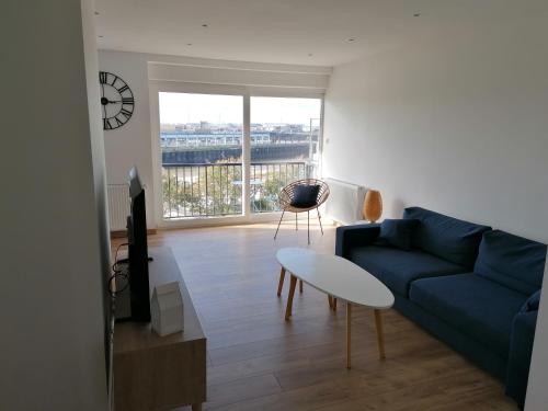 a living room with a blue couch and a window at T3 Nausicaa Parking gratuit in Boulogne-sur-Mer