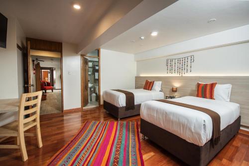 a hotel room with two beds and a living room at Casa Matara Boutique in Cusco
