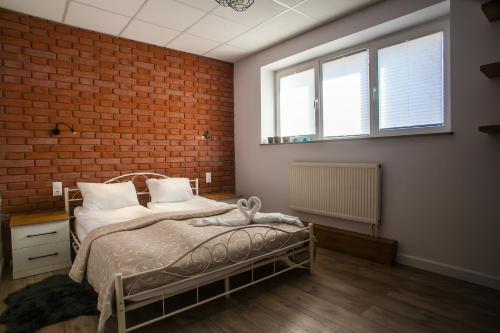 a bedroom with a bed and a brick wall at Main Street Chłodna Apartment in Suwałki