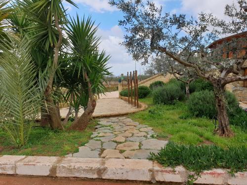 a stone path through a garden with palm trees at Agriturismo Duca di San Martino in Partanna