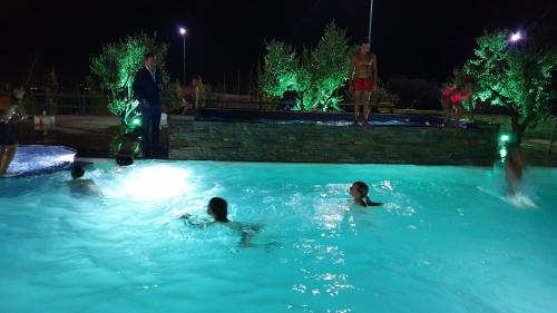 a group of people swimming in a swimming pool at night at Agriturismo Duca di San Martino in Partanna