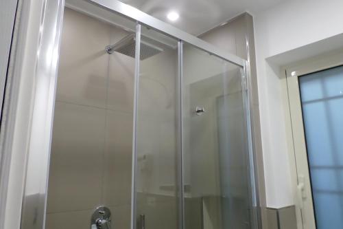 una doccia con porta in vetro in bagno di B&B Mansarda del Sole a Napoli