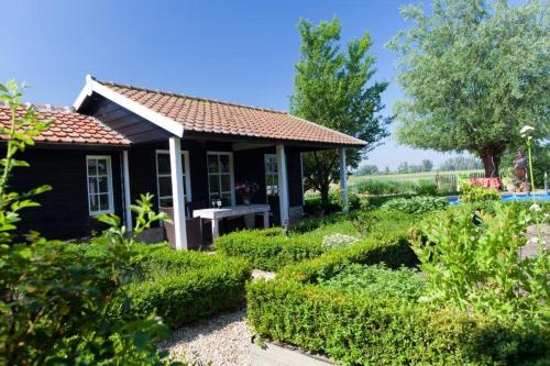 a small black house in a garden with bushes at In d'Ouwe Vlaamse Schuur in Ossendrecht