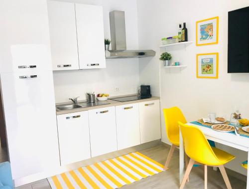a kitchen with white cabinets and a table with yellow chairs at Rome Temple House in Rome