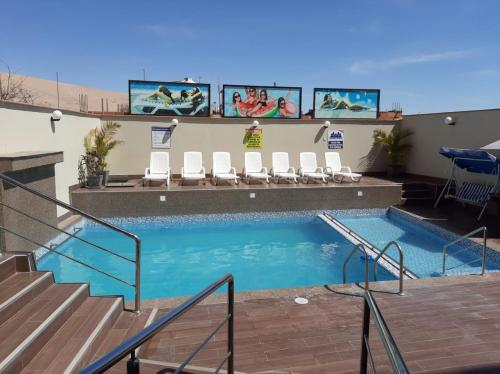 a swimming pool with chairs and stairs in a hotel at Hotel Spa Machupicchu in Tacna