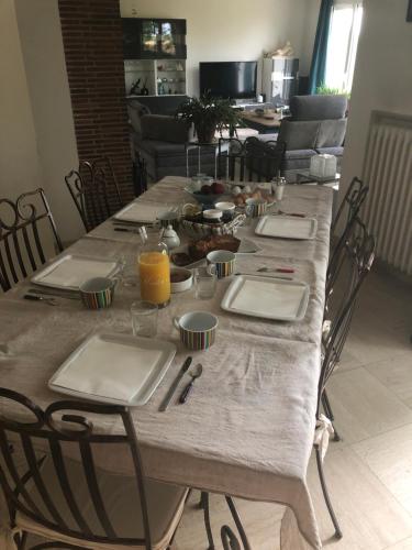 ein langer Tisch mit Stühlen, Tellern und Orangensaft in der Unterkunft Suite alcôve confort in Freneuse