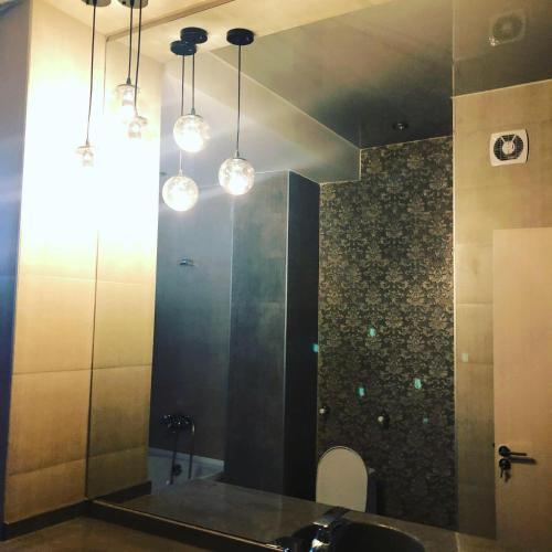 a bathroom with a sink and a mirror and lights at Dona Palace Apartments in Tbilisi City