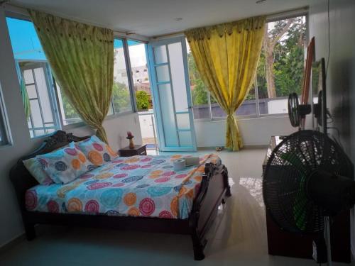 a bedroom with a bed and a fan and windows at Hospedaje casa Lucía in Leticia