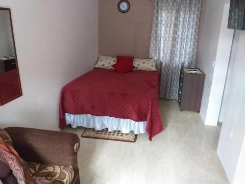 a small bedroom with a bed with a red blanket at Cozy Studio 2 in Kingston