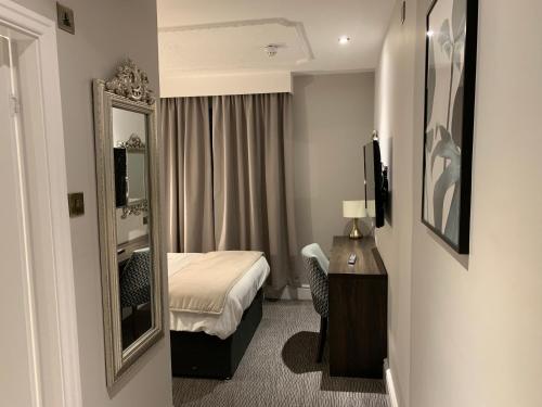 a hotel room with a bed and a mirror at Trafford Hall Hotel Manchester, Trademark Collection by Wyndham in Manchester