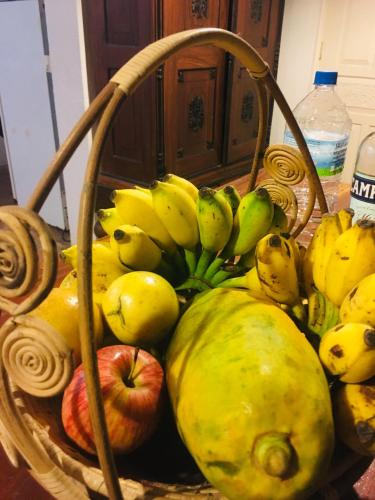 a basket full of bananas and apples on a table at Whispering House in Tangalle