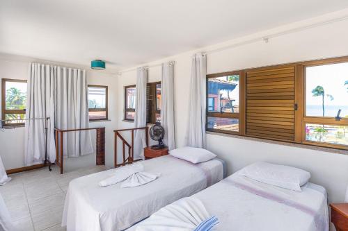 two beds in a room with two windows at Cumbuco Dream Village Duplex with 3 bedrooms in Cumbuco
