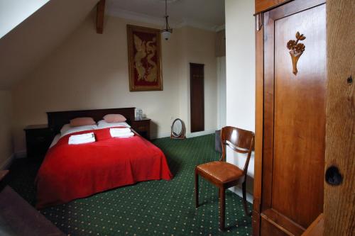 a bedroom with a red bed and a chair at Pałac Spichrz in Borcz