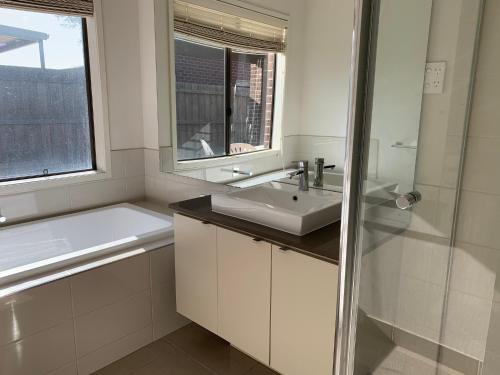 a white bathroom with a sink and a shower at Holiday Rental 6 KING BD 12PPL in Truganina