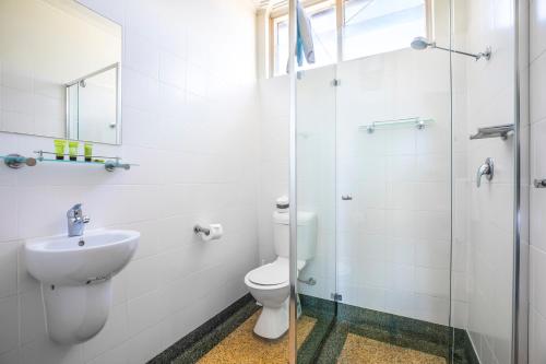a bathroom with a toilet and a glass shower at Links Hotel in Adelaide