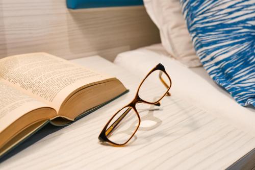 an open book and a pair of glasses on a bed at Hotel La Fiorita in Limone sul Garda