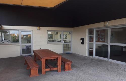 a picnic table and benches outside of a building at Opunake Beach Holiday Park in Opunake