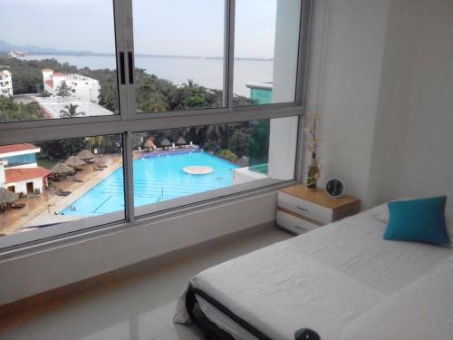 a bedroom with a view of a swimming pool from a window at Costa Azul Suites Apartamento 603 in Santa Marta