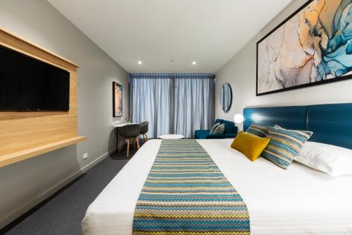 a hotel room with a large bed and a flat screen tv at Mercure Canberra Belconnen in Canberra