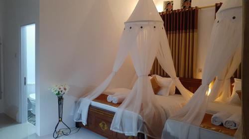 a bedroom with a bed with white drapes at Bintang Bungalow Tour & Travel in Kelimutu