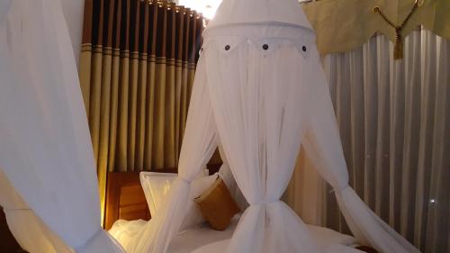 a bedroom with a bed with white drapes at Bintang Bungalow Tour & Travel in Kelimutu