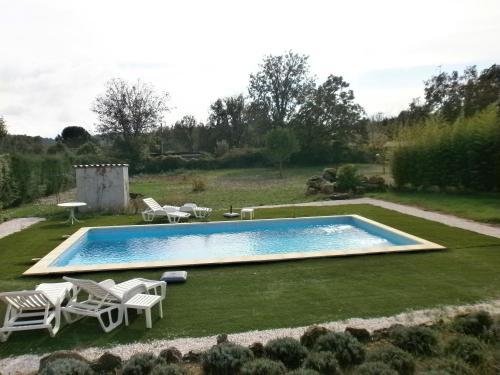 a swimming pool in a yard with some chairs at Les Tourterelles in Callian