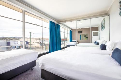 2 bedden in een hotelkamer met een groot raam bij Nightcap at Carlyle Hotel in Derwent Park