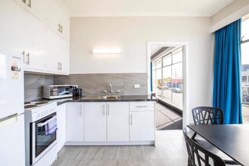 a kitchen with white cabinets and a dining table at Nightcap at Carlyle Hotel in Derwent Park