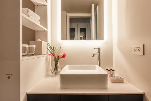 Hotel Renew في هونولولو: حمام مع حوض أبيض ومرآة