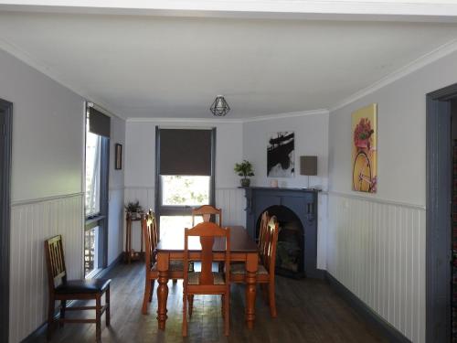 a dining room with a table and chairs and a fireplace at Welcome Stranger Cottage in Maryborough