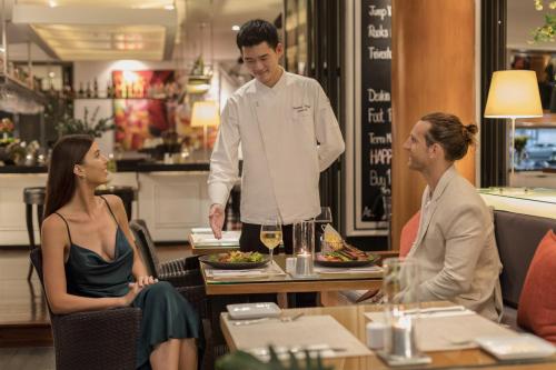 a chef standing in a restaurant with two people at BYD Lofts - Boutique Hotel & Serviced Apartments - Patong Beach, Phuket in Patong Beach