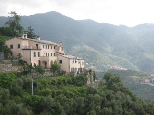 a house on a hill with mountains in the background at Tuvo Agriturismo in Levanto