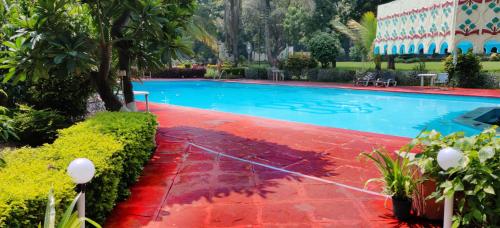 a swimming pool in a resort with a red floor at Ambassador Ajanta Hotel, Aurangabad in Aurangabad