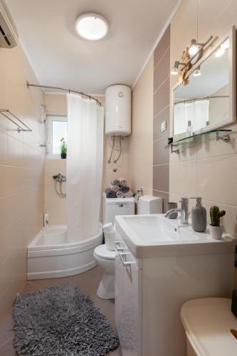 a bathroom with a sink and a toilet and a bath tub at Sea view Ela Apartments in Podgora