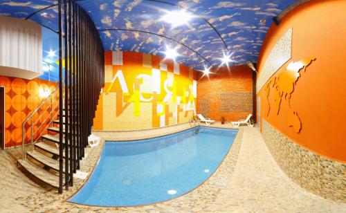 a swimming pool in a building with a mural on the ceiling at Guest House Lisya Nora in Psebay